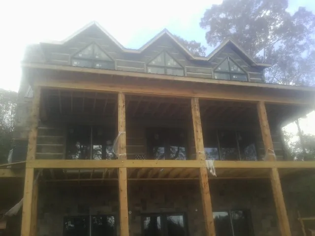 Dormers and porch framing on a large log home under construction — Roof Coating work by our crew in New Lisbon